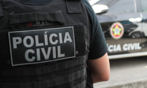 Foto de viatura da Polícia Civil do Rio de Janeiro estacionada em frente a uma delegacia, com foco no emblema da instituição. Ao fundo, movimentação de agentes durante o dia.