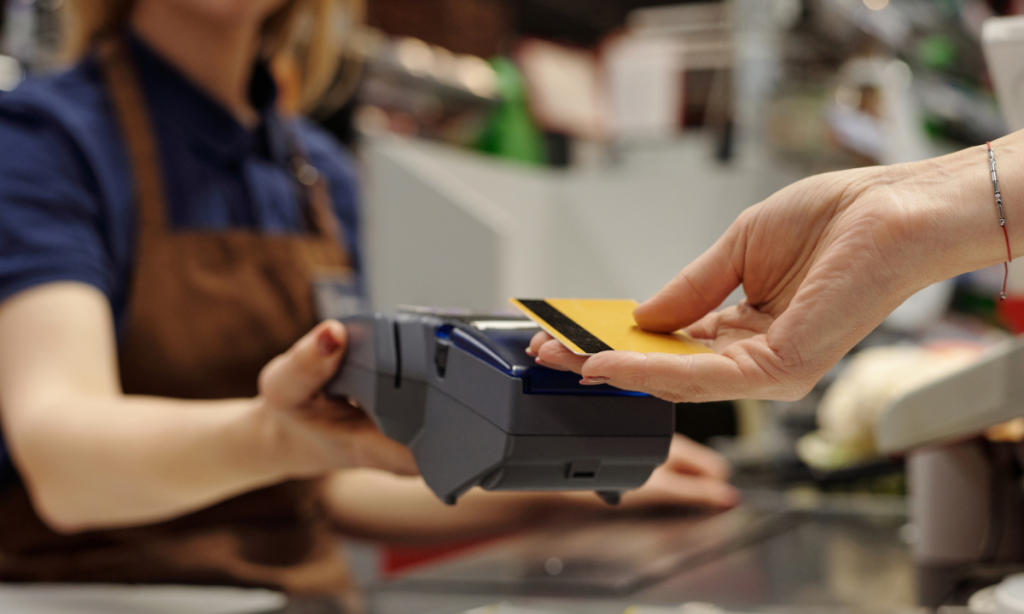 Cliente fazendo compra com cartão mostrando o momento do pagamento com cartão passando na maquina de crédito, e solicitando a nota fiscal para o programa NitNota