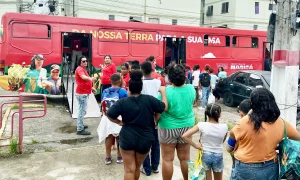 Funcionários do ônibus vermelho distribuindo verduras e frutas para moradores de Maricá em fila