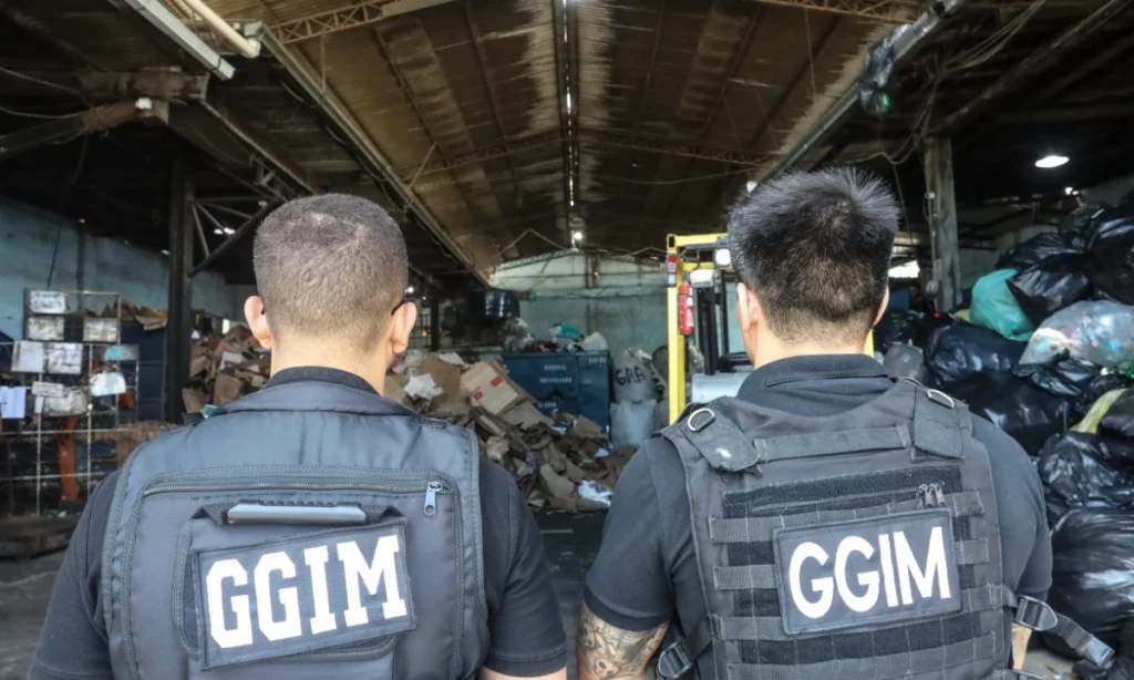 Agentes da Força Tarefa de costas observam um depósito com materiais