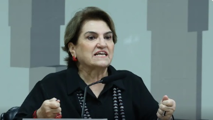 A ministra das Mulheres, Márcia Lopes, fala ao microfone durante evento no BNDES, no Rio de Janeiro. Ao fundo, painéis institucionais indicam o anúncio de investimentos para mulheres empreendedoras.